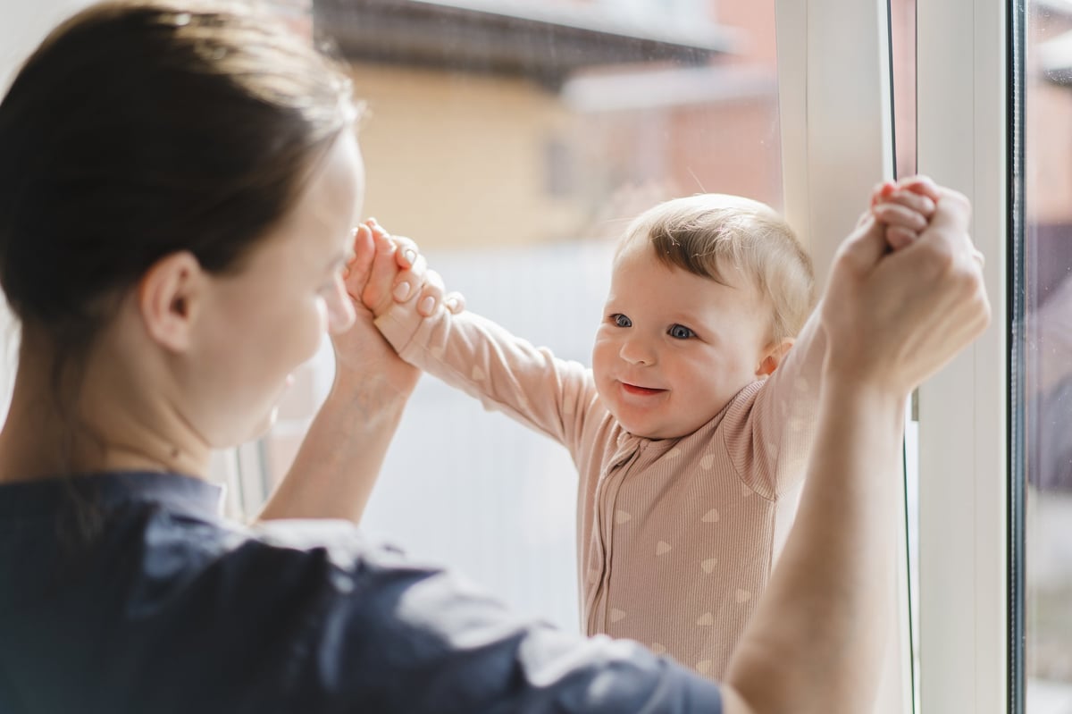 Mother talking face to face with her baby in warm window light