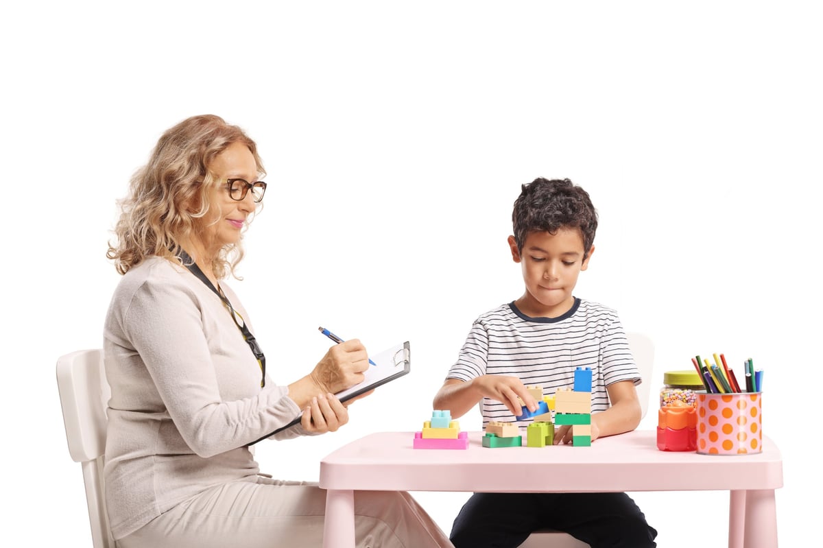 Therapist watching a young child play with toys during a session
