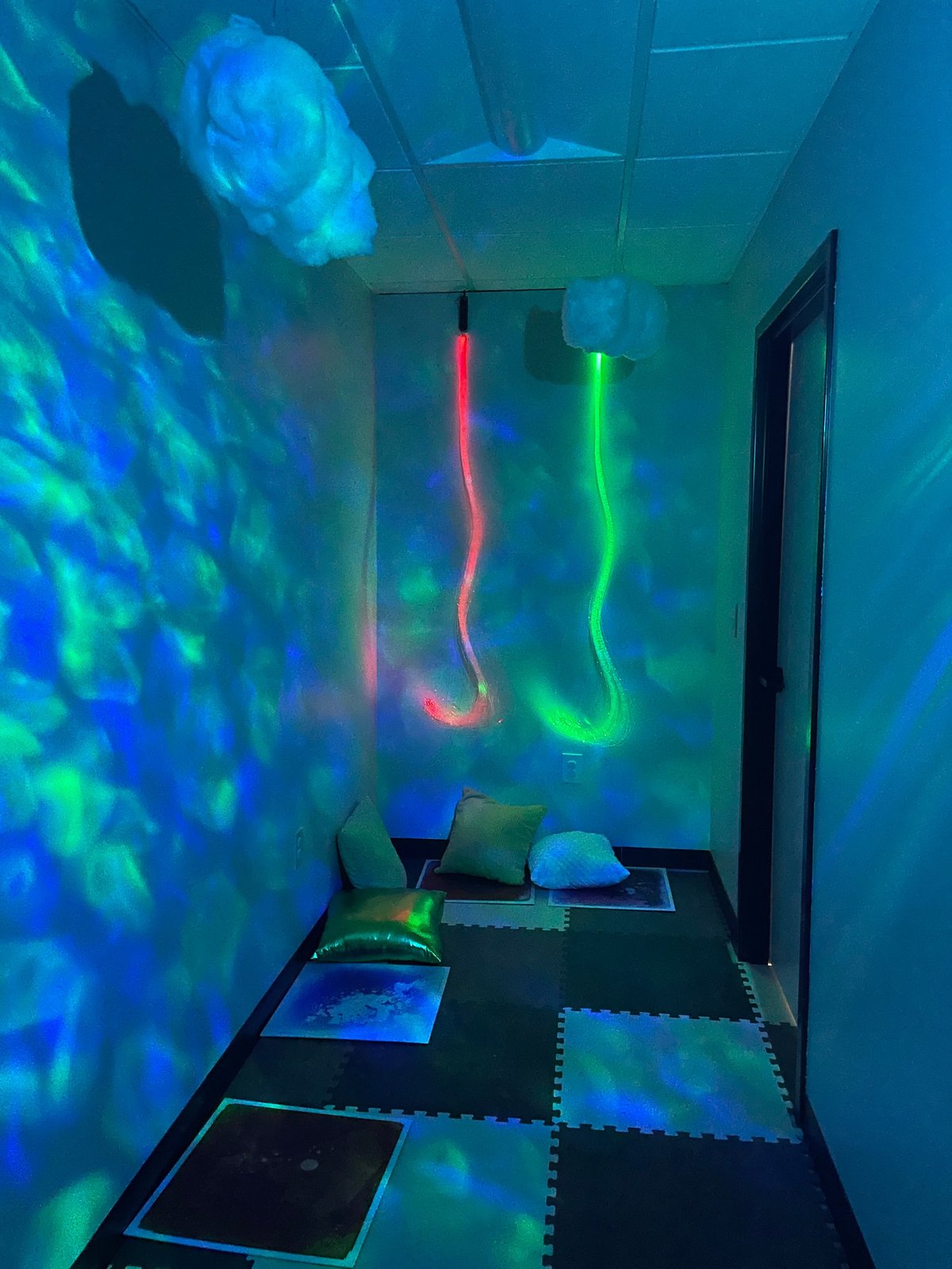 Sensory room with glowing tubes and projection lighting at New Heights Therapy in Topeka, Kansas — a calming space used in pediatric occupational therapy