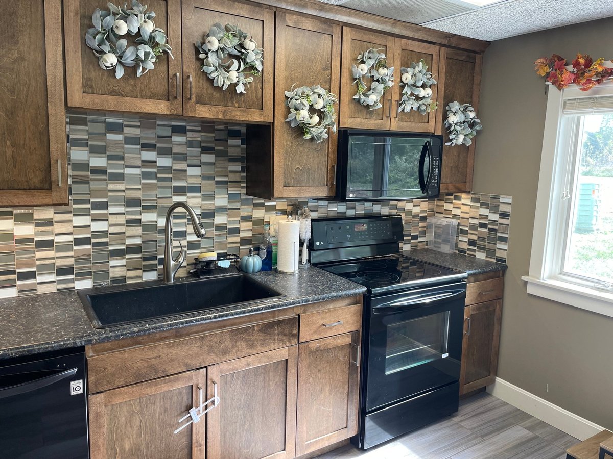 Wood cabinets, checkered tile backsplash, black granite countertops and black appliances in the teaching kitchen at New Heights Therapy in Lawrence, Kansas