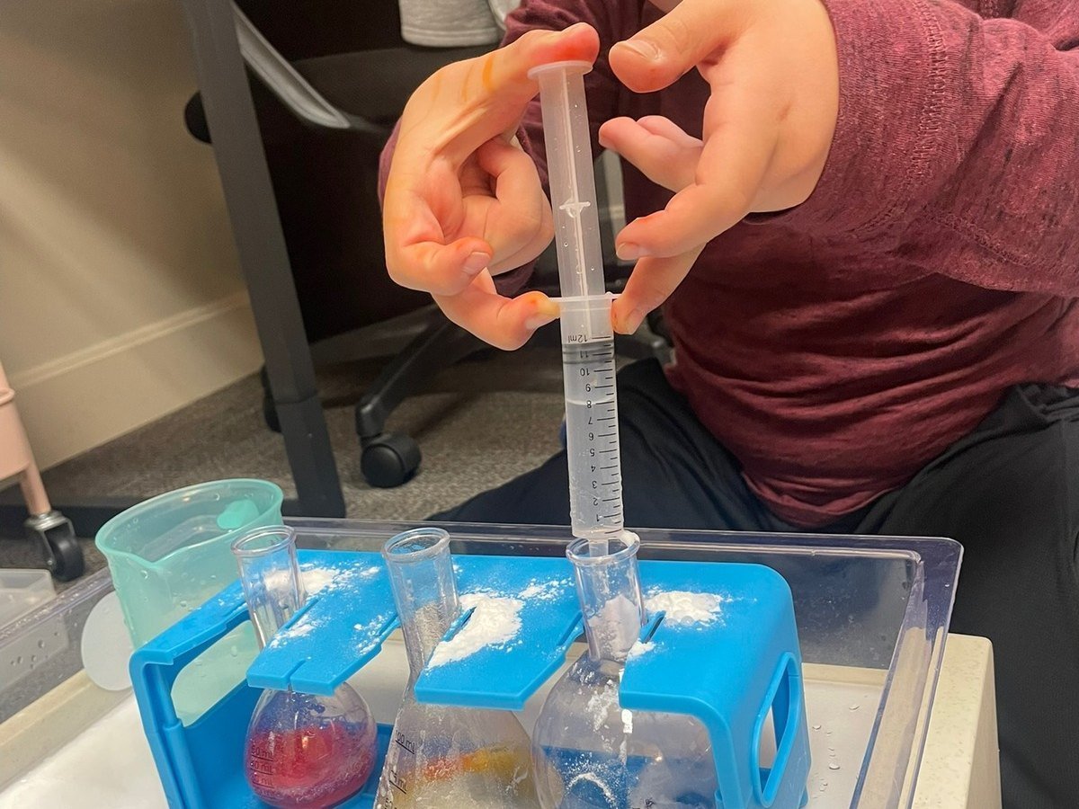 Hands using a syringe in a colourful science experiment, a fine motor skills activity in occupational therapy