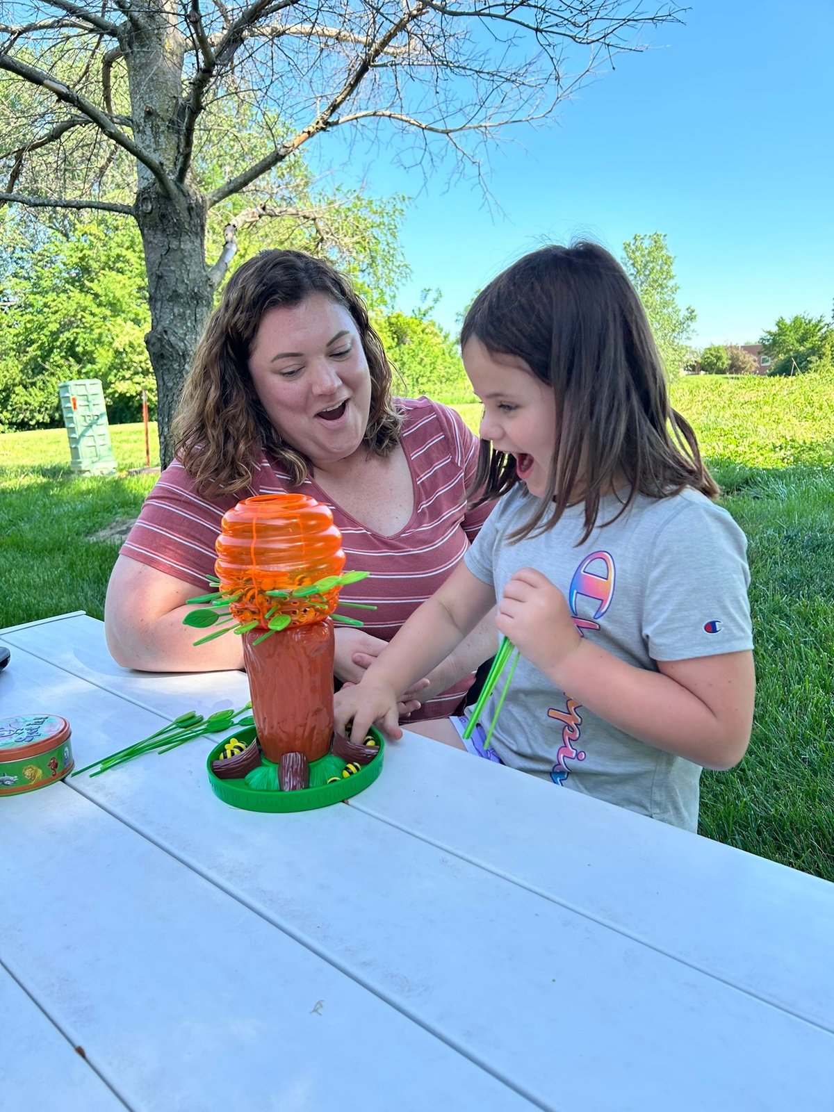 Speech therapist playing with a young child at an outdoor table with a toy on a sunny day — speech and language practice that fits real life