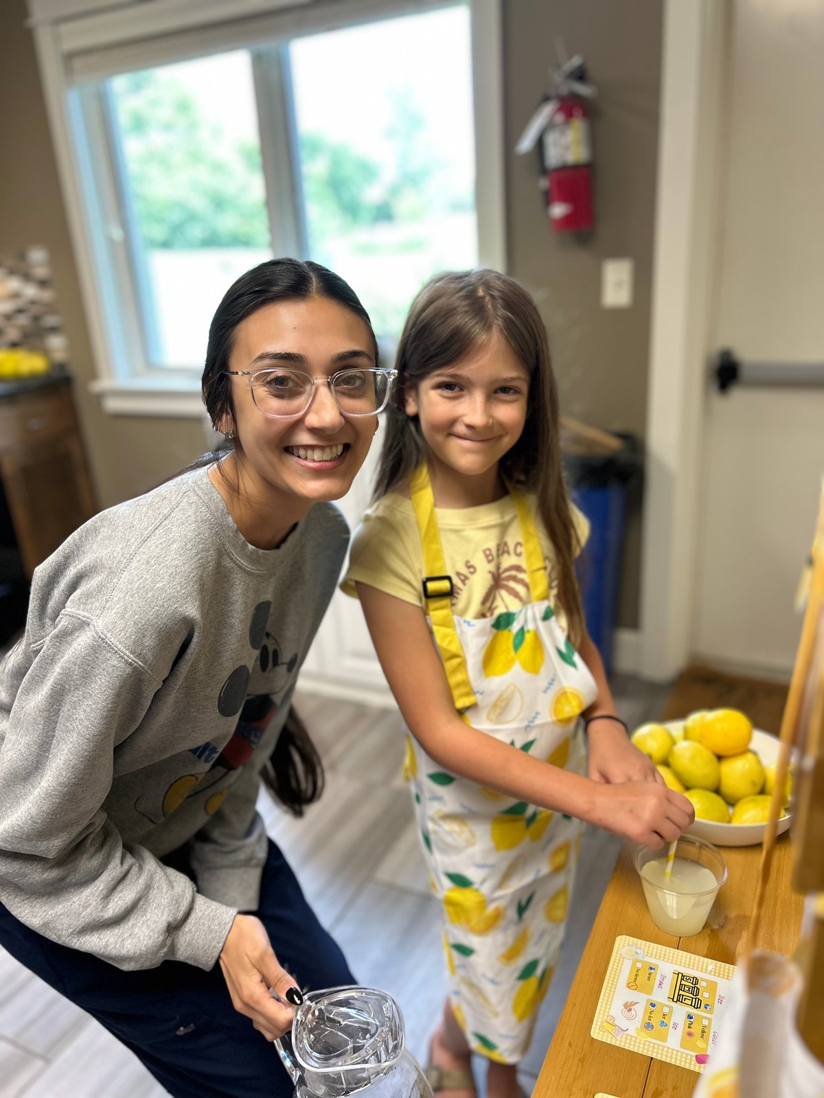 Speech therapist and a young girl at a pretend lemonade stand, practicing language and social communication through pretend play