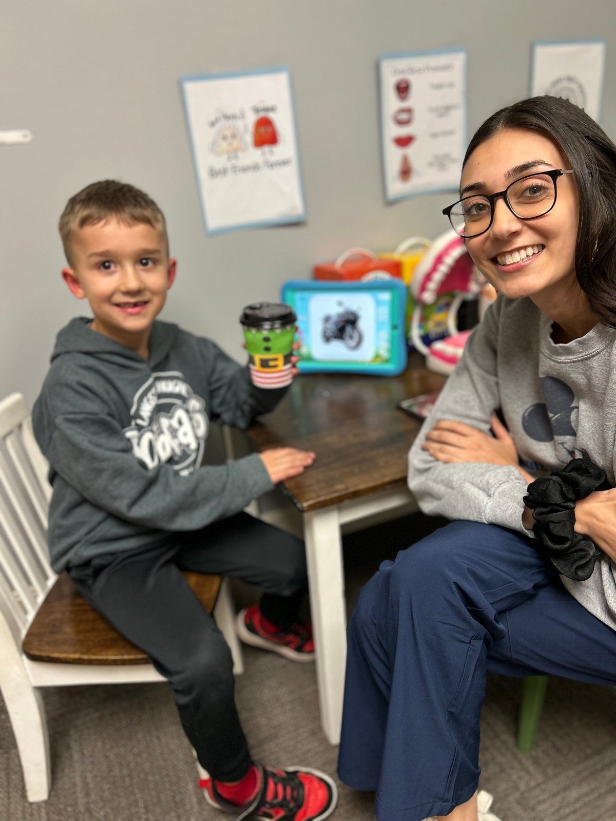 Speech therapist and a young boy playing with colorful educational toys at a bright therapy table