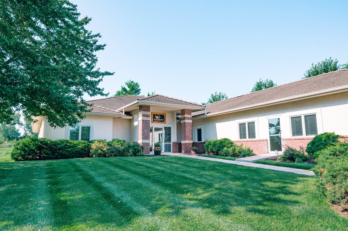 Exterior of the New Heights Therapy clinic in Lawrence, Kansas, a ranch-style building with a columned front porch and landscaped lawn