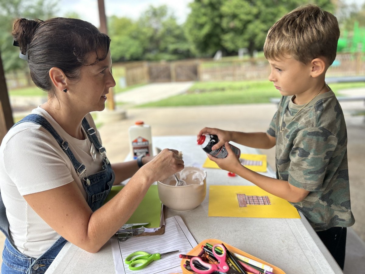 Therapist and child working on an outdoor shaving cream craft at a table, building fine motor skills in occupational therapy