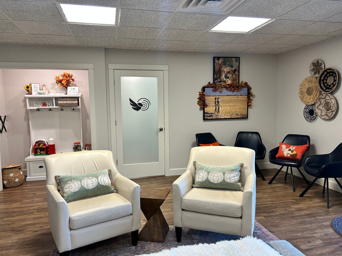 Waiting room with two white armchairs and the New Heights Therapy logo on the door