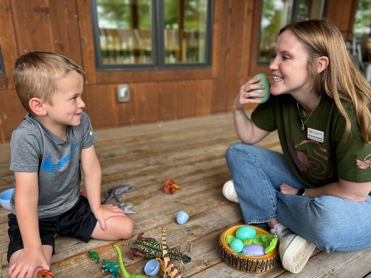 Young boy and woman playing with colorful toy balls and objects on wooden floor indoors