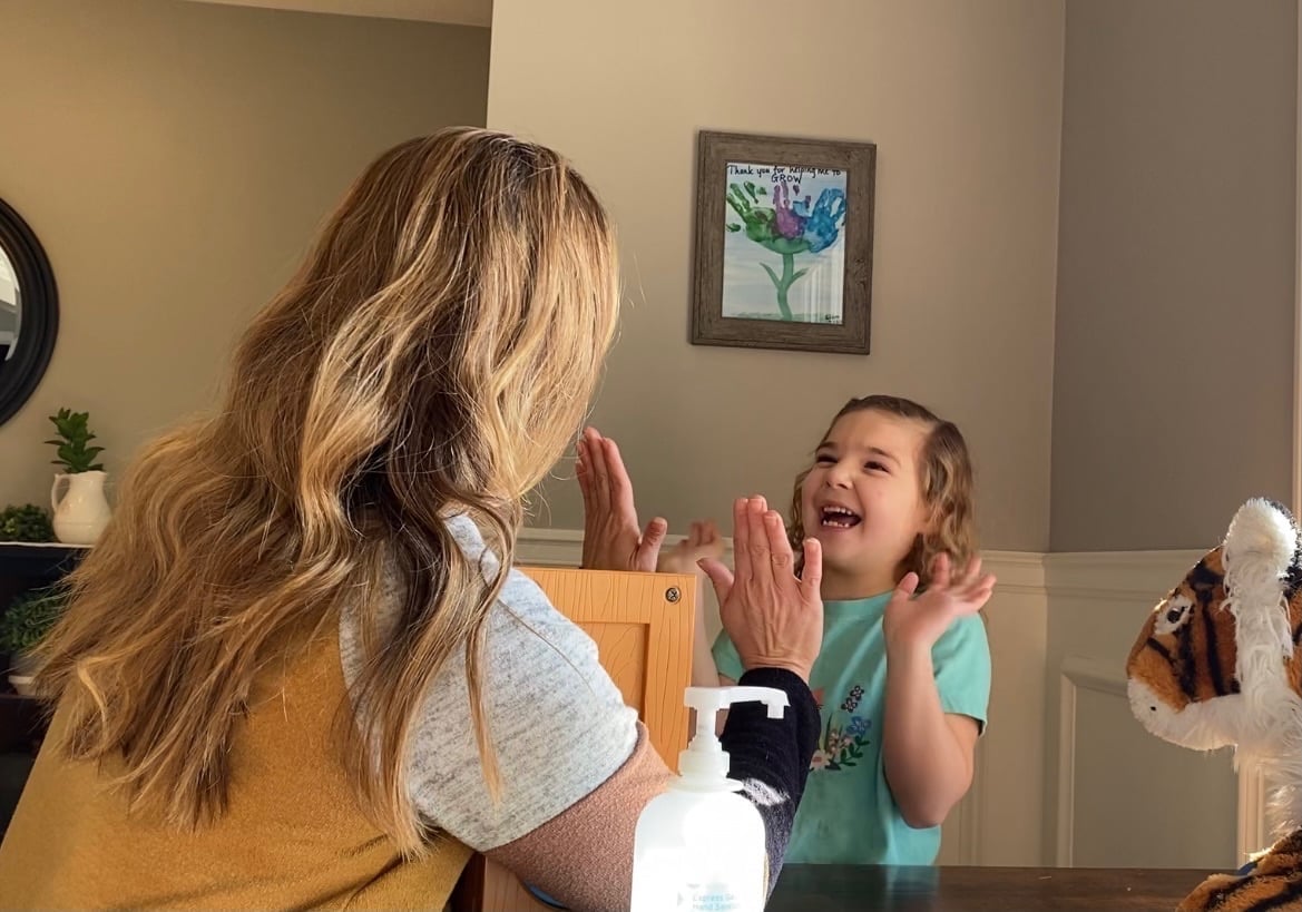 Pediatric therapist sharing an enthusiastic high five with a young girl in a green shirt during a session at New Heights Therapy in Kansas.