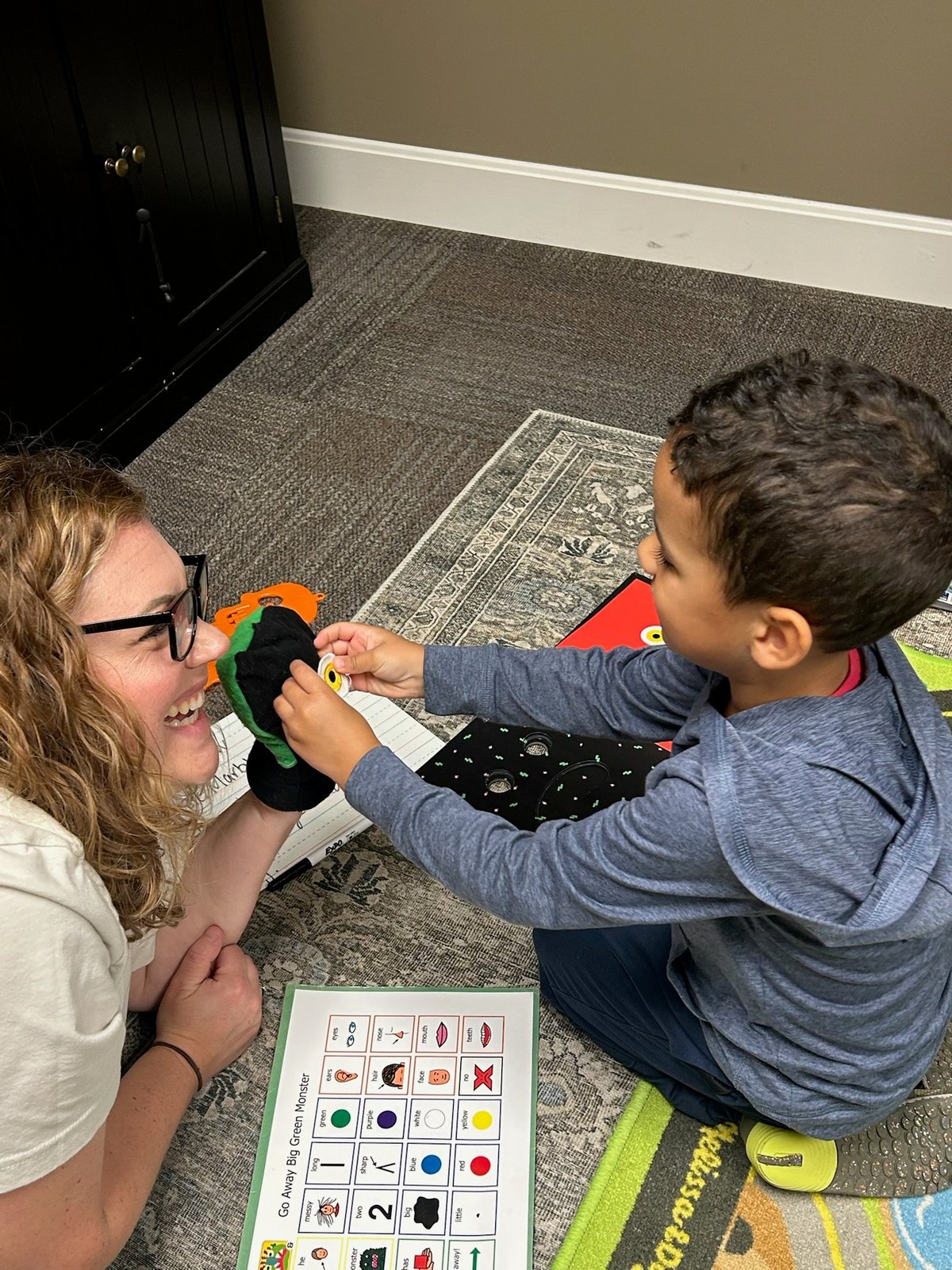 Two children on a colorful mat working on a Rubik's cube together — a speech therapy activity that builds turn-taking and conversation