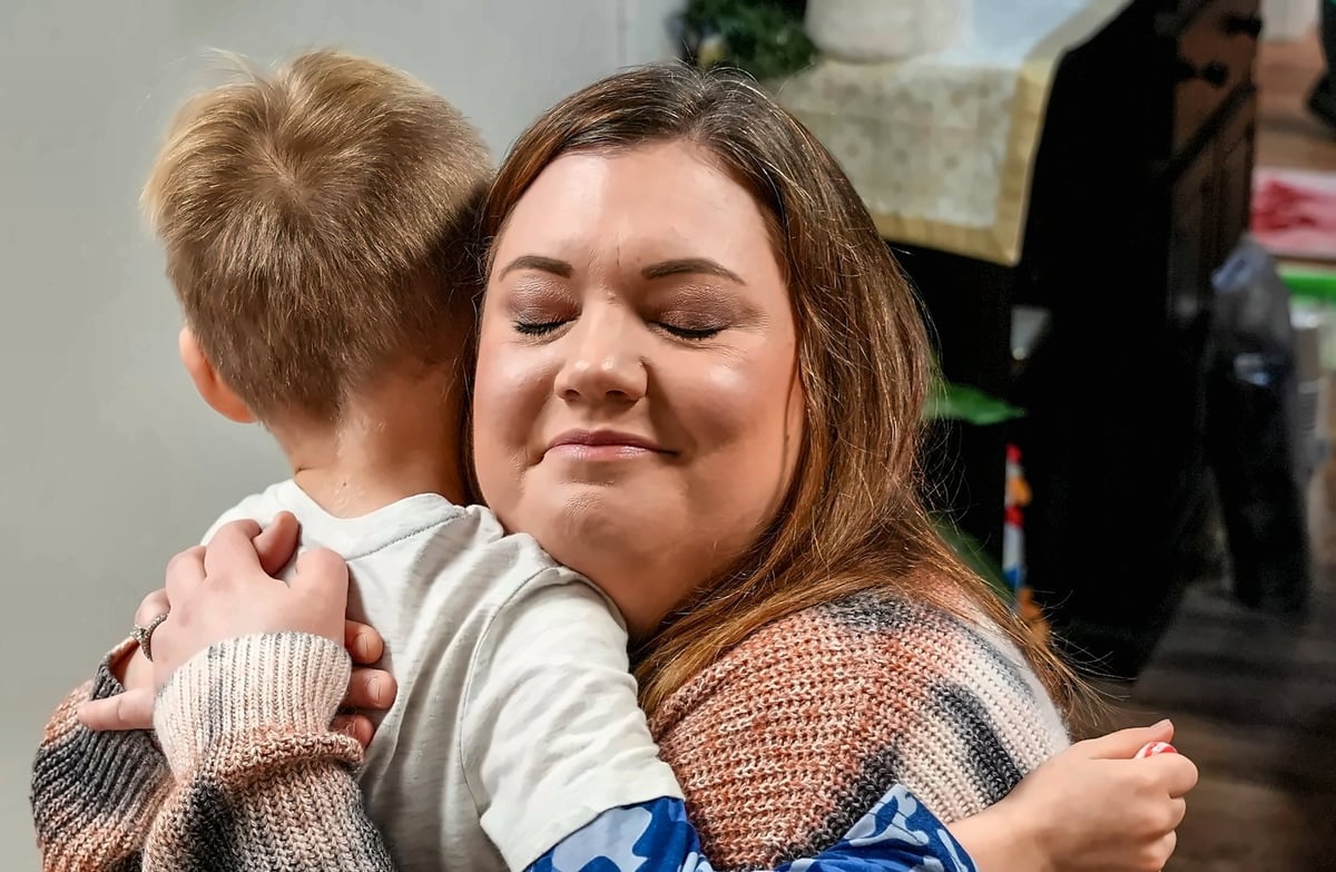 Speech therapist celebrating with a young child resting on her shoulder after a speech therapy session at New Heights Therapy